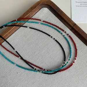 Gros plan de colliers en argent S925 avec perles de turquoise et agate sur bois