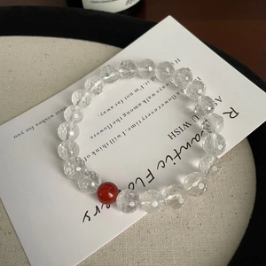 Close-up of faceted clear crystal beads and a vibrant red agate bead on a display card