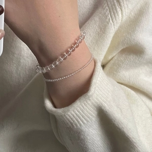 Detail of clear crystal beaded bracelets on white knit sweater for a minimalist fashion look