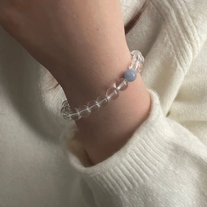 Vue détaillée d'un bracelet en aigue-marine et cristal blanc sur un poignet et pull en tricot