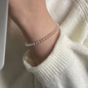 Detailed close-up of a minimalist clear crystal bead bracelet worn on a female wrist