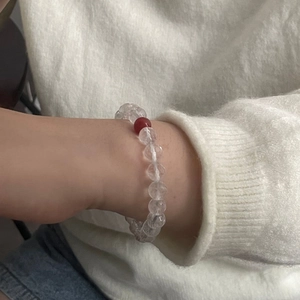 Detail view of clear faceted crystal beaded bracelet with a red agate accent on wrist