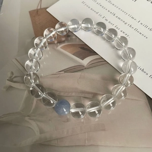 Vue détaillée des perles en cristal blanc et aigue-marine sur une pochette crème douce
