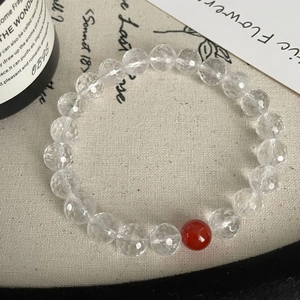 Macro view of faceted white crystal beads and red agate on a minimalist beaded bracelet