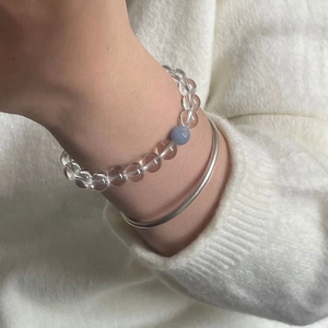 Gros plan d'un bracelet en cristal d'aigue-marine superposé à un jonc en argent chic