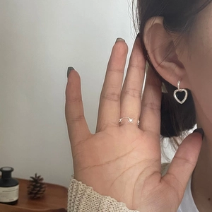 Detail shot of 925 silver double hoop heart earrings and dainty bow ring on a model