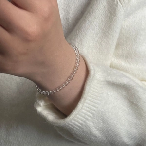 Detailed view of clear white crystal beaded bracelet worn over a cozy white knit sweater