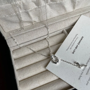 Detail der 925 Sterling Silber Fischtall-Halskette mit flüssigem Metallanhänger auf Beigegewebe