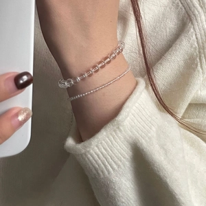 Detail of elegant white crystal beaded bracelets on wrist with soft knit background