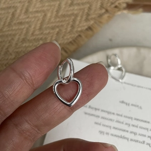 Detailed close-up of 925 sterling silver hoop earrings with hollow heart charms