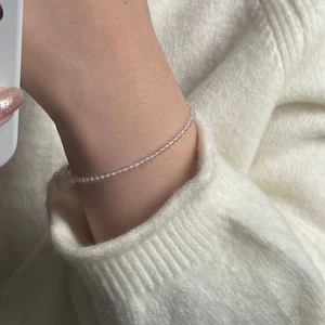 Close-up of minimalist beaded silver bracelet with white crystals on a wrist