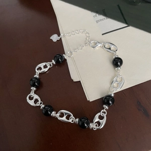 Macro detail of S925 sterling silver pig nose link and black agate beaded bracelet