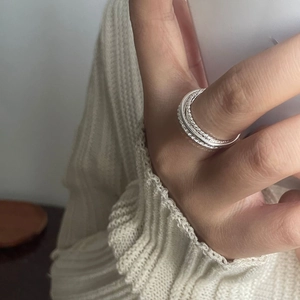 Close-up of layered S925 sterling silver twist rings on model's finger with soft knitwear