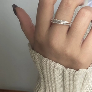 Detailed view of stacked S925 sterling silver twist rings worn with a knit sweater