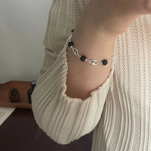Detailed close-up of S925 silver link bracelet with black agate beads on a model's wrist
