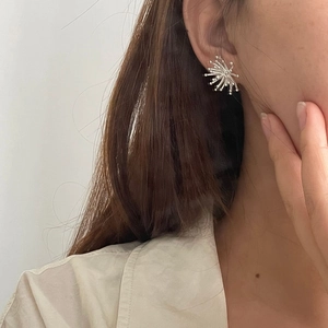Close-up of minimalist S925 sterling silver starburst fireworks earrings on a model