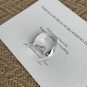 Macro shot of polished 925 silver irregular U-shape ring on a textured card background