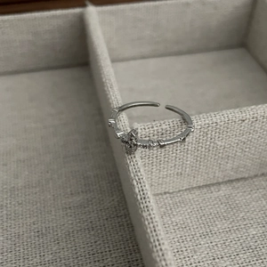 Macro shot of silver cross ring with cubic zirconia and beaded band detail