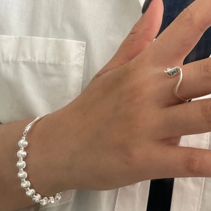 Detailed shot of irregular U-shaped silver ring and beaded bracelet on hand
