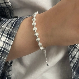 Detail showing 925 silver beaded bracelet with brushed texture on plaid shirt background