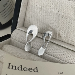 Macro shot of minimalist liquid metal 925 silver earrings on premium linen jewelry box