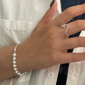 Close-up of minimalist 925 sterling silver wavy ring and beaded bracelet on hand