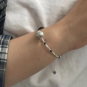 Détail du bracelet en perles d'argent S925 avec oeil de chat et breloque coeur au poignet