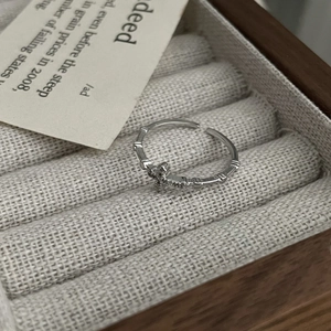 Macro shot of silver cross ring with cubic zirconia and bamboo textured band detail