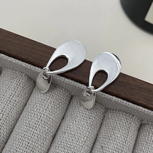 Macro shot of 925 sterling silver hollow teardrop earrings on a wooden jewelry display