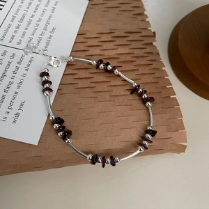 Macro detail of S925 sterling silver beads and dark red garnet stones on handmade bracelet