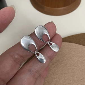 Close-up of hand holding double teardrop 925 silver earrings with mirror polished finish