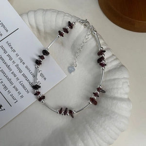 Macro shot of S925 sterling silver beads and garnet stones on a white textured plate