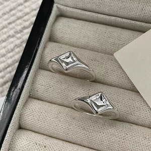 Bagues minimalistes en argent sterling 925 losanges sur un plateau à bijoux beige texturé