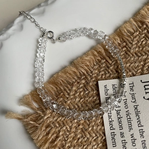 Detail eines facettierten weißen Kristallarmbands mit silbernem Verschluss auf Leinen