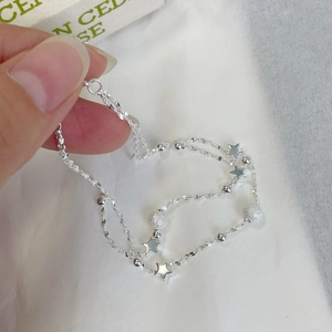 Detailed close-up of double-layered silver bracelet with stars and frosted beads