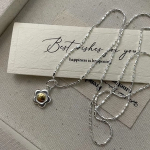 Detailed view of S925 silver daisy necklace with golden core on a canvas background