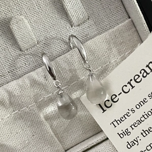 Macro detail of S925 silver earring with a translucent teardrop gemstone on fabric