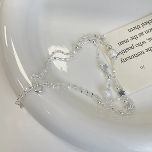 Detail view of silver double-layer star bracelet with frosted beads on white ceramic tray