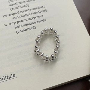 Detailed close-up of polished S925 silver double-layered beaded ring on vintage book page