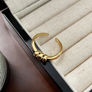 Macro detail of gold plated S925 sterling silver knot ring in a beige jewelry box