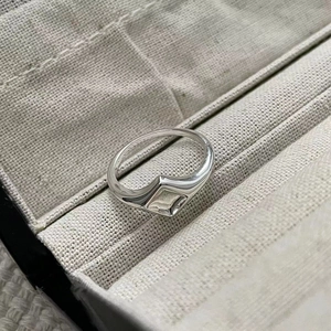 Vue macro d'une bague chevalière géométrique en argent sur une boîte en tissu gris