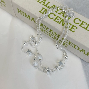Macro detail of silver double-layered star bracelet with frosted beads on packaging