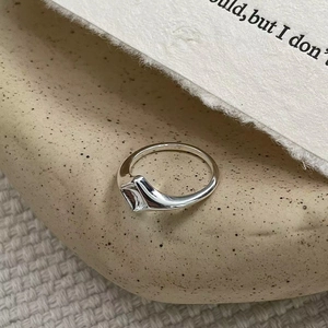 Gros plan détaillé d'une bague géométrique en argent S925 sur un fond minimaliste texturé