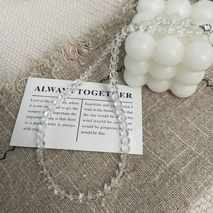Détail d'un collier de perles en cristal avec fermoir argenté sur tissu en lin