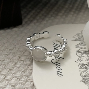 Dettaglio anello a sfere in argento S925 con gemma bianca tonda su biglietto regalo