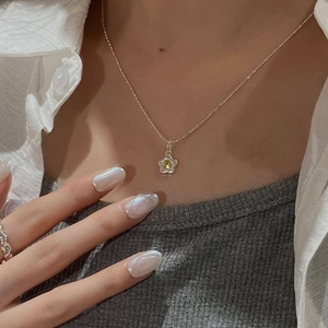 Close-up of S925 sterling silver sun flower necklace and wavy ring worn by model