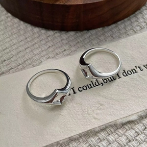 Vue macro de deux bagues géométriques en argent sterling 925 sur une surface en tissu texturé