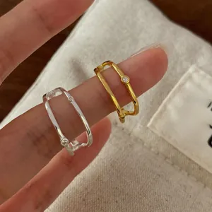 Detail view of double-layered silver and gold minimalist rings with tiny zircon stones