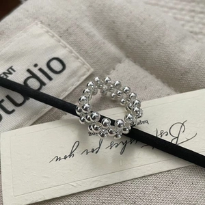 Macro shot of silver beaded ring with hand-woven texture on a stylish prop background