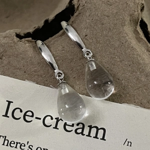 Macro shot of minimalist S925 sterling silver earrings with clear waterdrop glass pendants